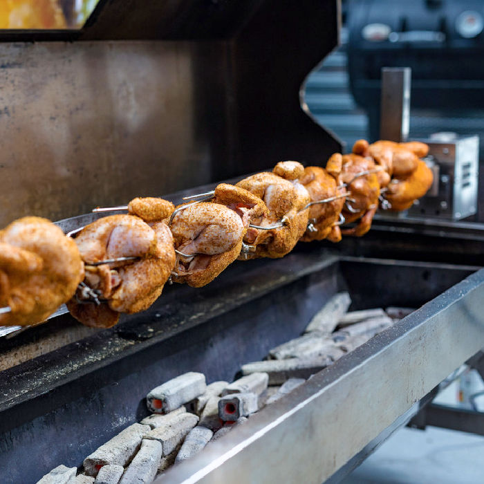 a spit showing a full spit of meat cooking over charcoal