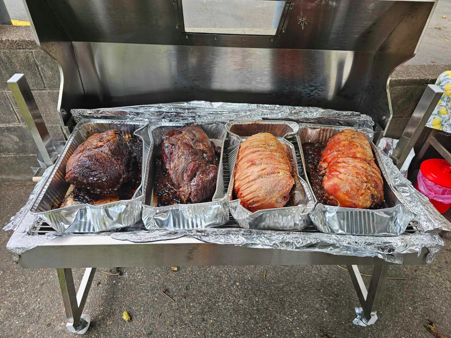 1200 spartan hooded charcoal spit used as an oven with pork and beef slow cooking