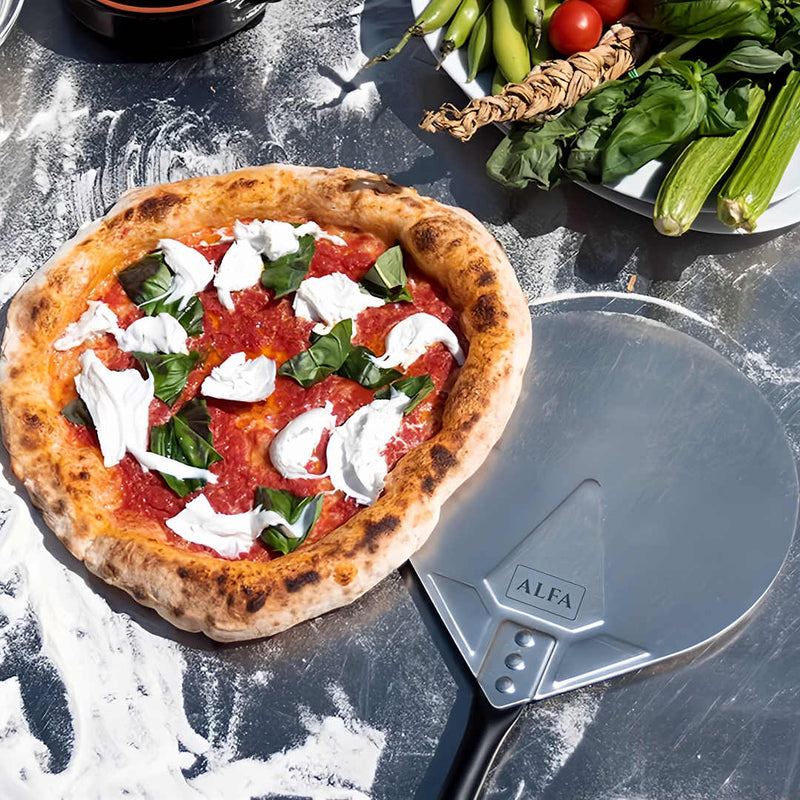 Alfa Pizza Oven Tool Kit Large pizza peel turner sitting next to a cooked pizza