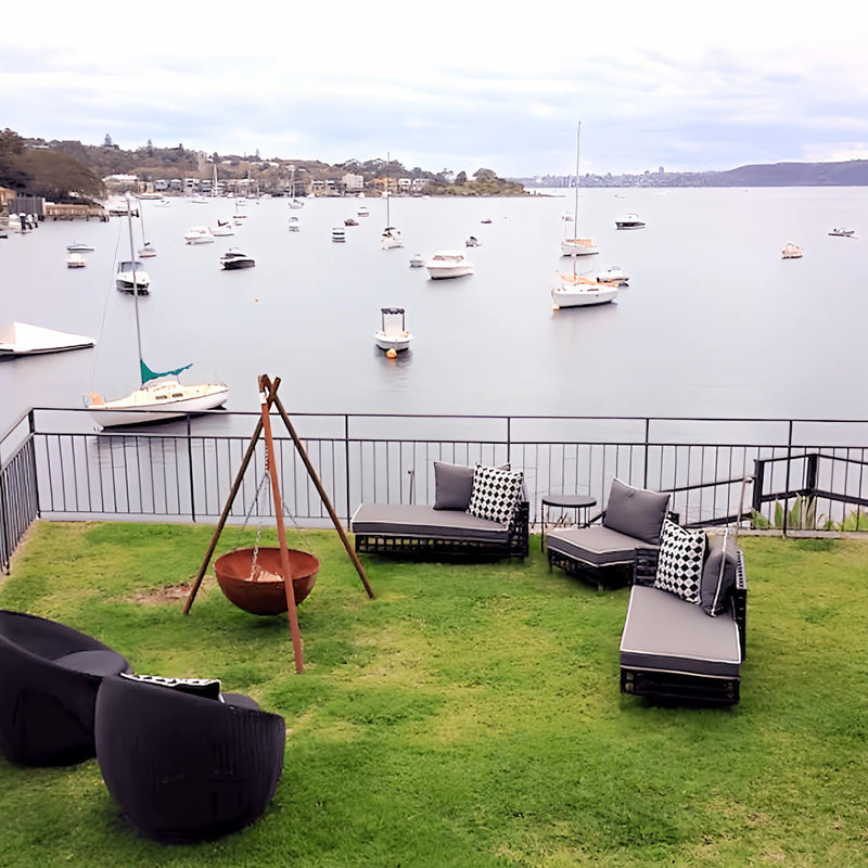 Tripod Fire Pit zoomed out view in outdoor area with canal in background