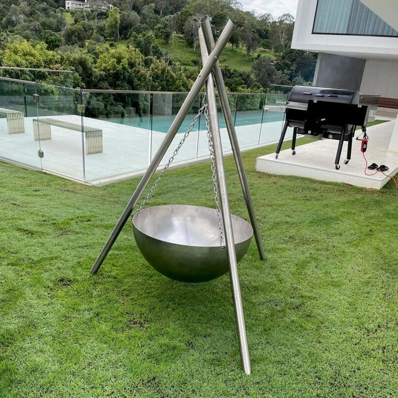 Tripod Fire Pit | The Inferno Tower | Cast Iron & Stainless Steel in the stainless steel version sitting in a backyard