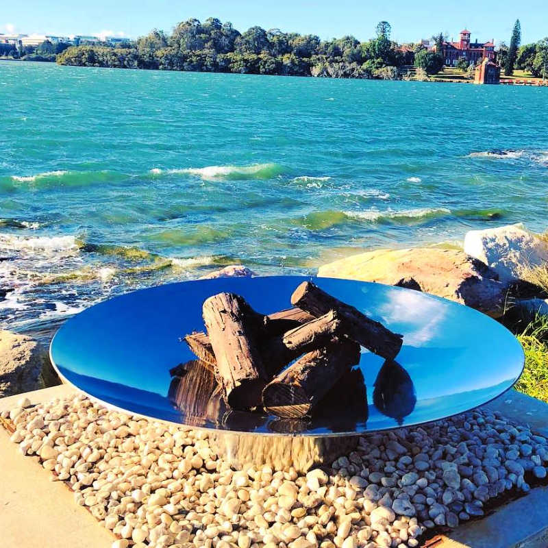 Outdoor Fire Pit: The Outdoor Fire Pit and Stinless Steel Grill bundle near the beack with wood inside