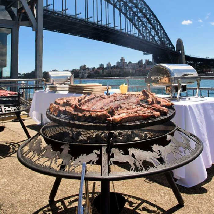 BBQ fire pit grill cooking meat sitting next to the sydney harbour bridge