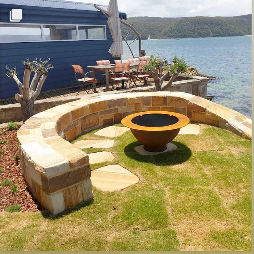 The Teppanyaki cast iron fire pit from outdoor living australia in a backyard with a scenic view