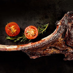a large rib steak on the bone with garnishes around it