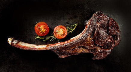 a large rib steak on the bone with garnishes around it