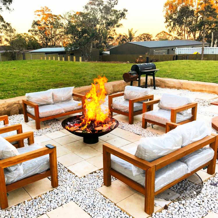 Fire pit in an outdoor setting with a smoker in the background