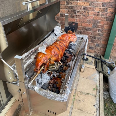 a whole pig ona  1500 spit rotisserie cooking showing one of our hire cooks