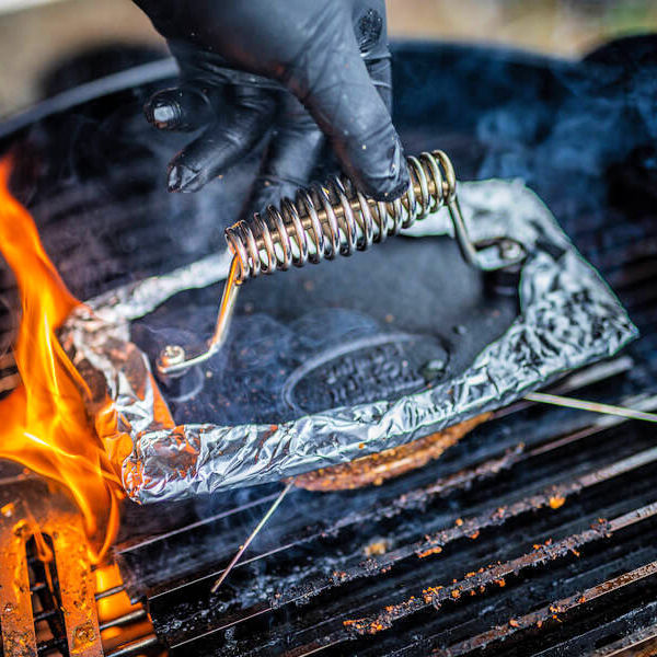 Cast Iron Burger Press | close up top view of burger press with a guys hand pushing down on a meat patty