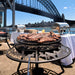 BBQ Grill and Fire Pit with cowboy design full of meat on grill with bridge in background