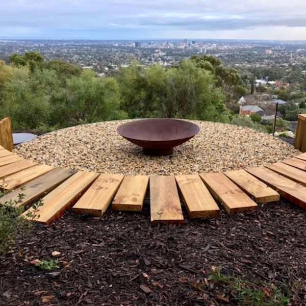 cauldron fire pit sitting looking over a bush and town