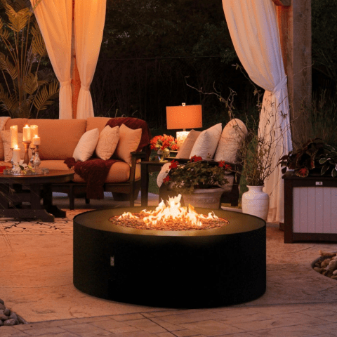 A gas fireplace in an outdoor setting with the flame on at night