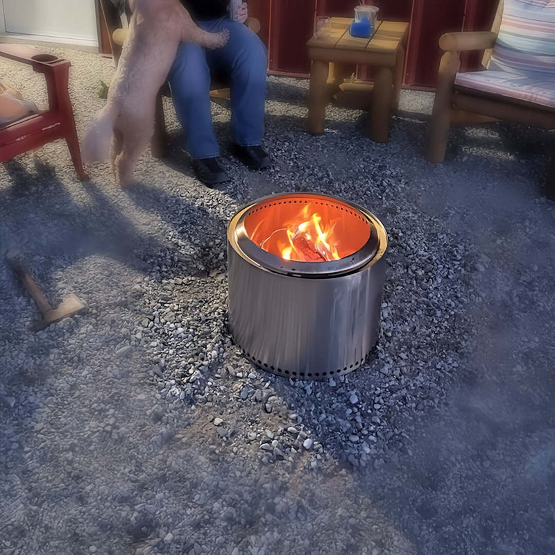 Smokeless Fire Pit | zoomed out view with fire inside and person sitting next to it