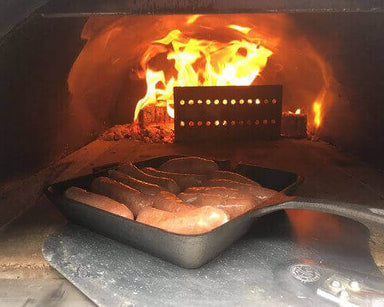 Stainless Steel Log Holder | in pizza oven holding back flames while cooking sausages