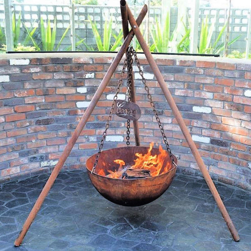 Tripod Fire Pit front view with fire inside near brick wall