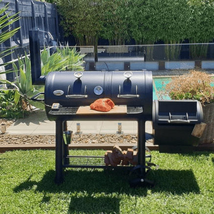 An offset BBQ smoker with some meat prepared and ready to put inside